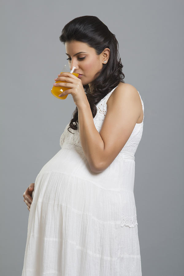 Pregnant woman drinking a glass of orange juice Photograph by Sudipta Halder