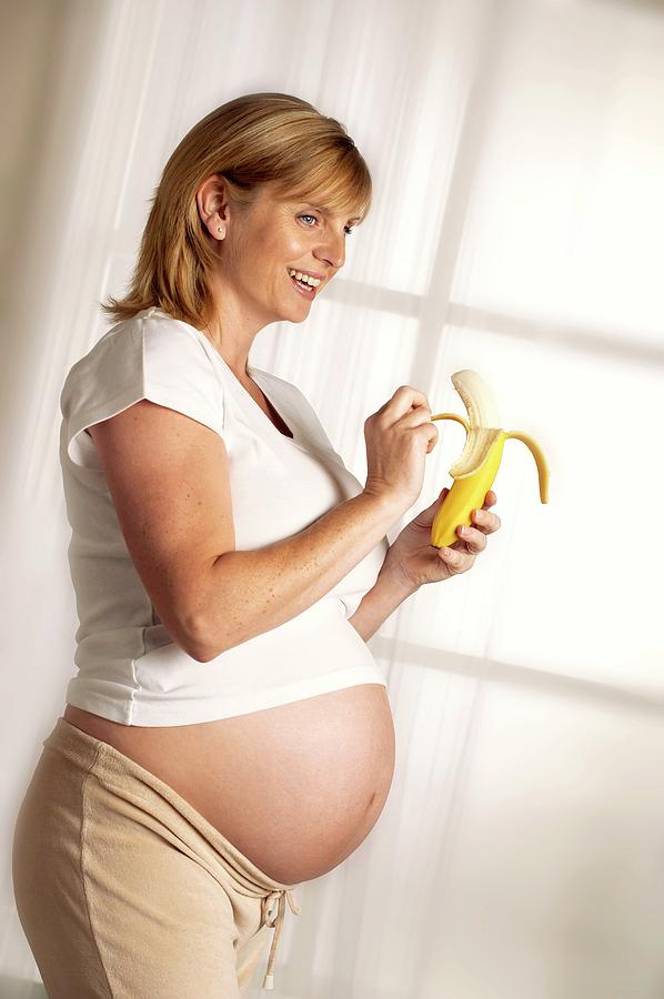 Pregnant Woman Eating A Banana Photograph by Mark Sykes