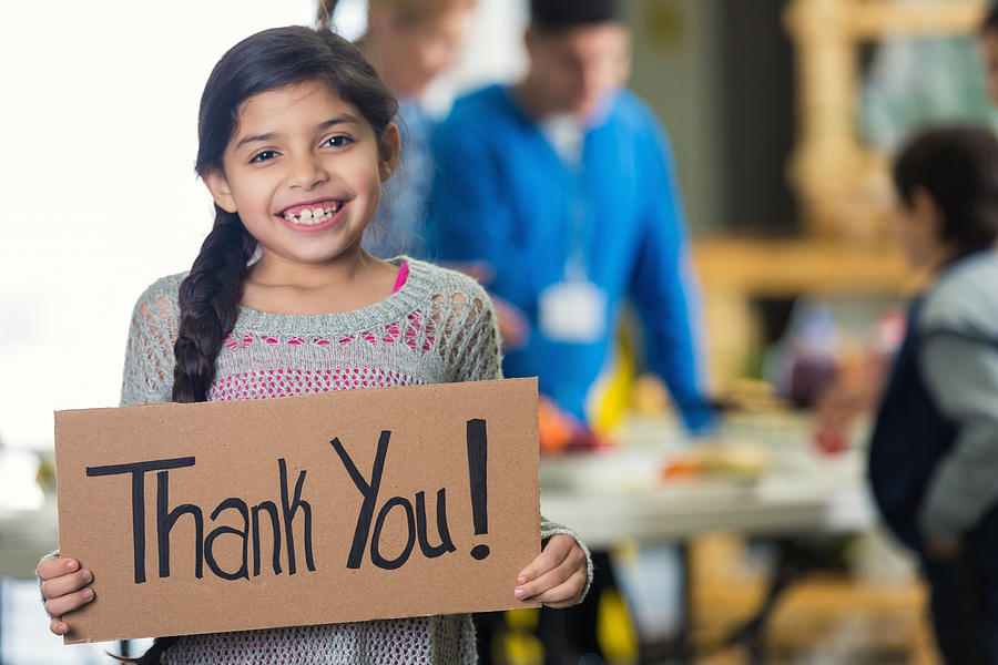 Pretty Hispanic girl holds Thank You! sign in soup kitchen Photograph by SDI Productions