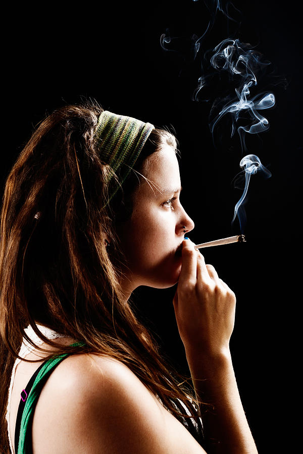 Pretty pot head thoughtfully smoking marijuana joint. Photograph by RapidEye