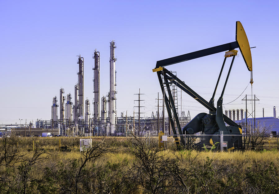 Pumpjack (oil derrick) and refinery plant in West Texas Photograph by Dszc