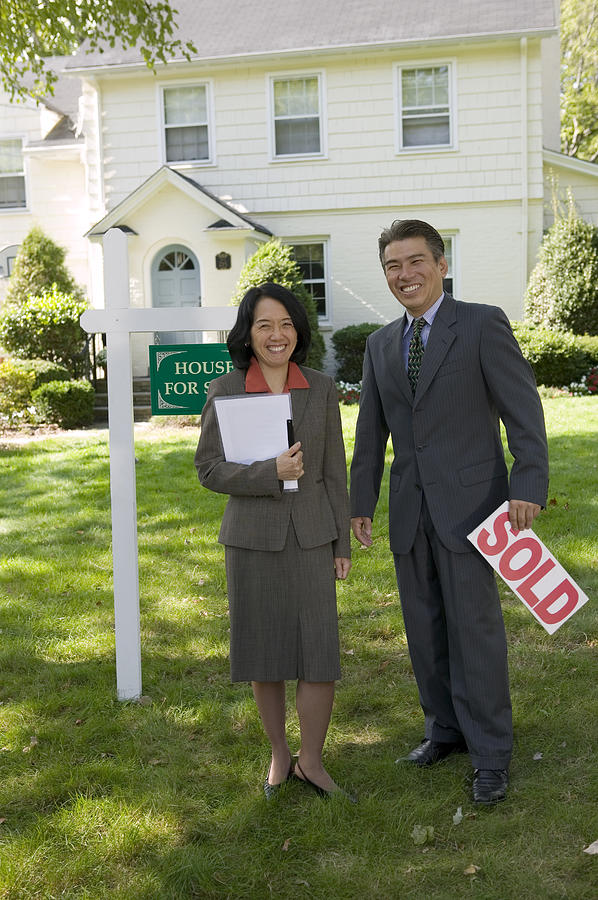 Realty agents with sold sign Photograph by Comstock Images