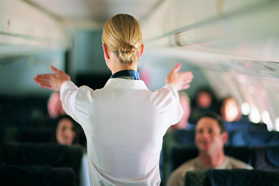 Rear View of Air Stewardess Explaining Aeroplane Safety to Passengers Photograph by James Lauritz