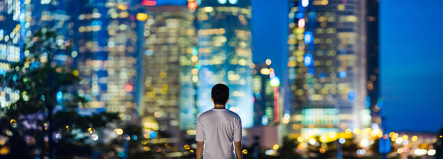Rear view of man overlooking illuminated city skyline of Hong Kong Photograph by D3sign