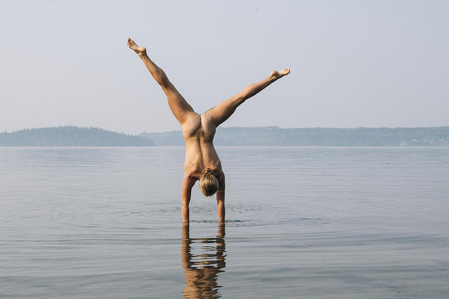 Rear view of nude woman doing handstand in water Photograph by Pete Saloutos
