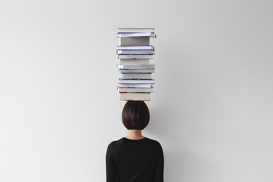 Rear view of woman with stack of books on her head Photograph by Pchyburrs