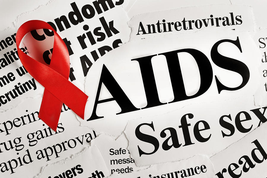 Red AIDS ribbon on headlines concerning the disease Photograph by RapidEye
