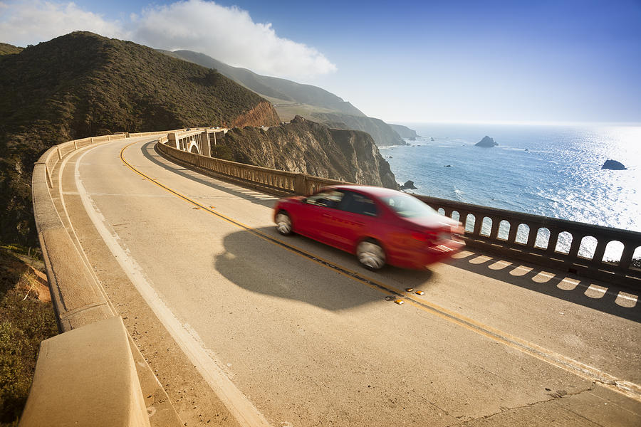 Red car zooms down Bixby Bridge in Big Sur Photograph by Pgiam