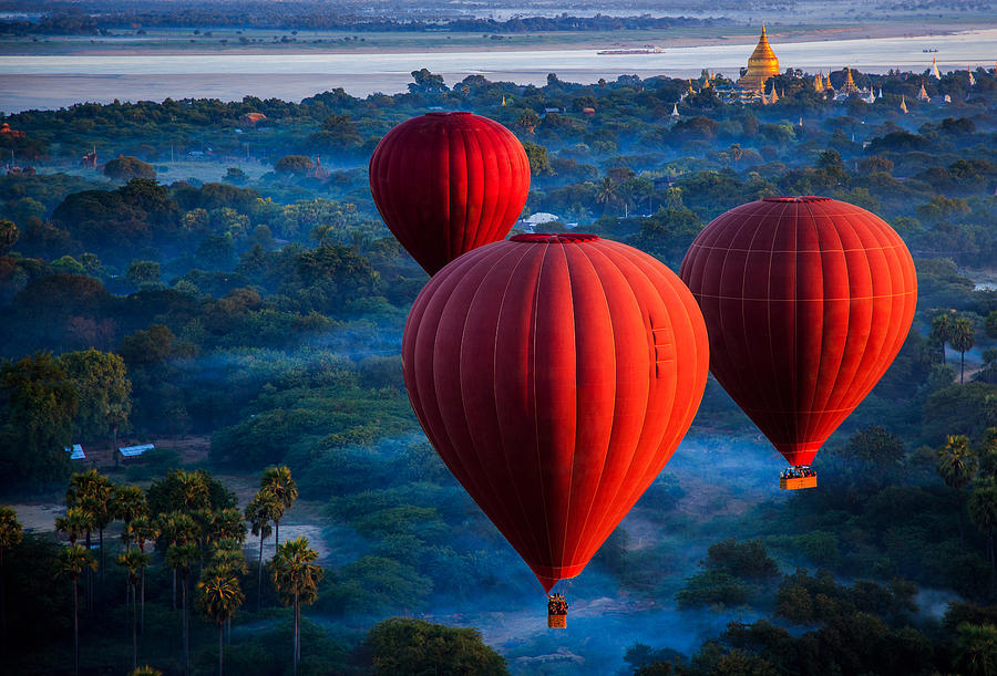 Red hot air balloons over jungle, Nyaung-U, Mandalay Region, Myanmar Photograph by JP Klovstad