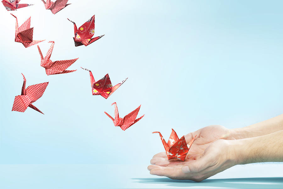 Red origami cranes flying away from hands Photograph by Paper Boat Creative