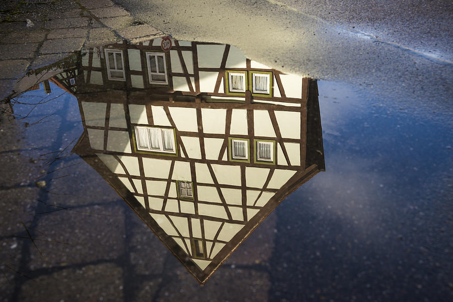 Reflection of a beautiful old half-timbered house in a puddle of water Photograph by Matthias Hauser