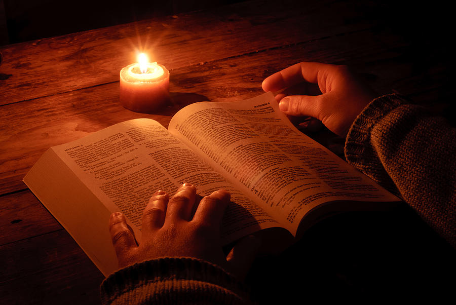 Relaxing and reading bible by candlelight at night Photograph by PaulCalbar