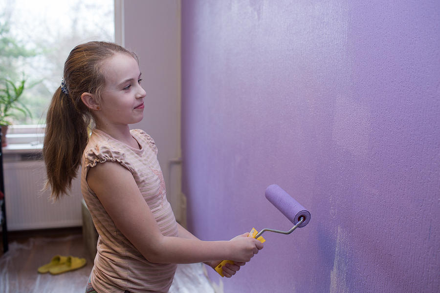 Repairs in the apartment. Girl paints the wall with ultraviolet paint - trend 2018 Photograph by TatyanaTitova