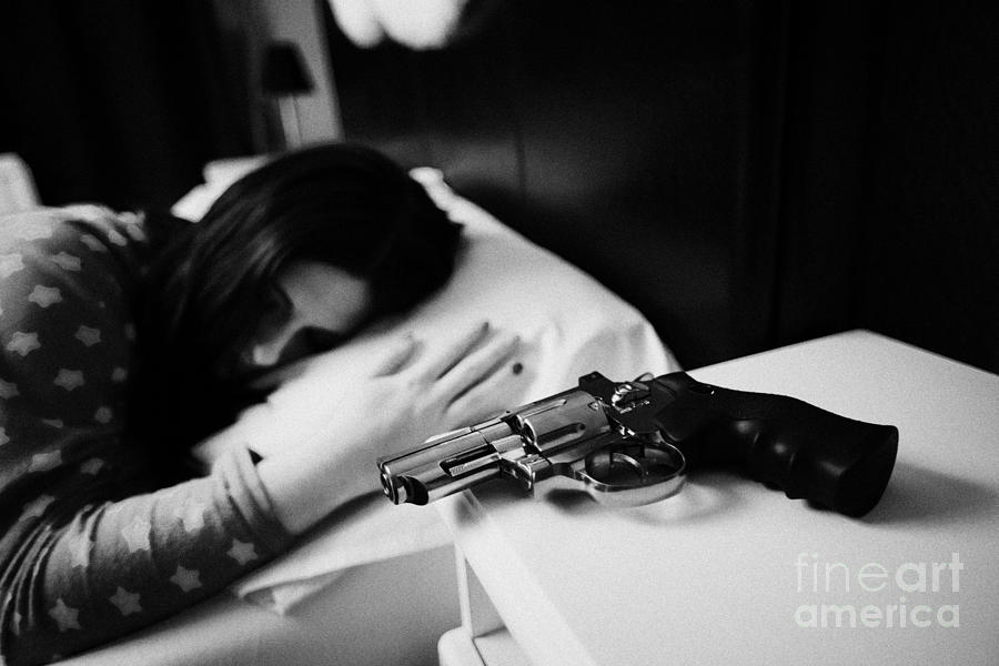 Revolver Handgun On Bedside Table Of Early Twenties Woman In Bed In A