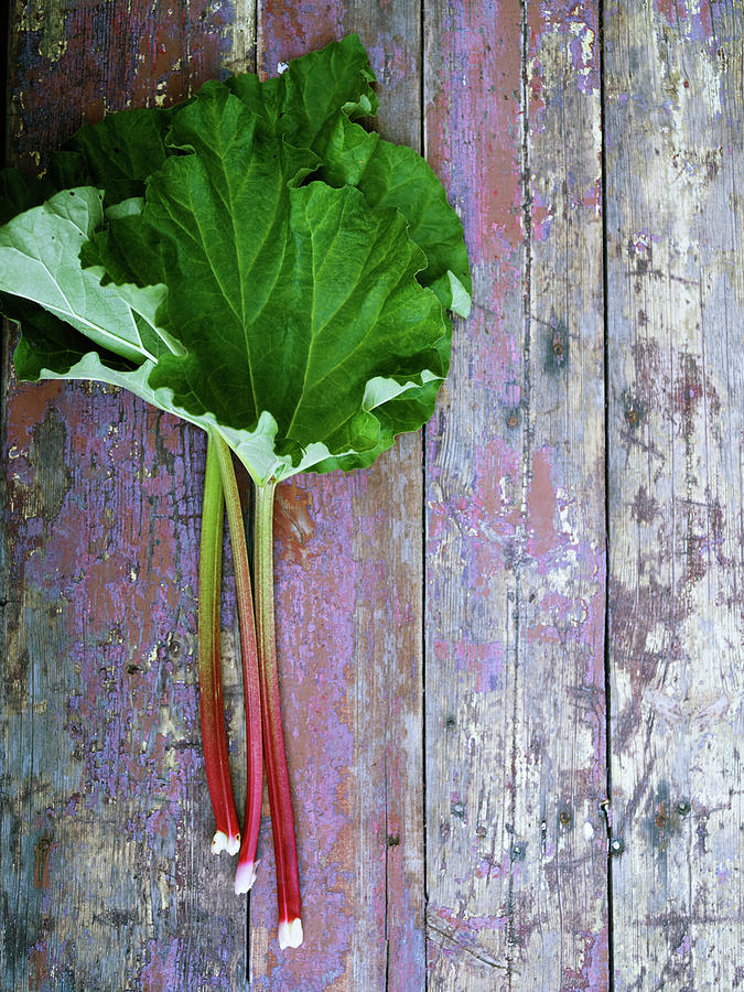 Rhubarb Leaves On Wooden Surface Photograph by Johner Images