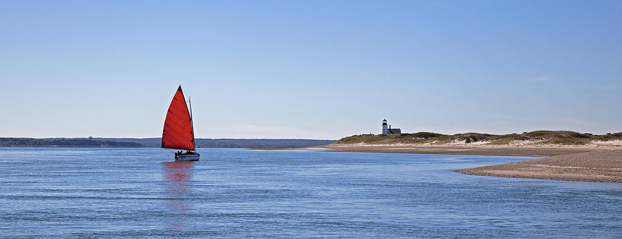 Ripple Catboat with Red Sail and Lighthouse Photograph by Charles Harden