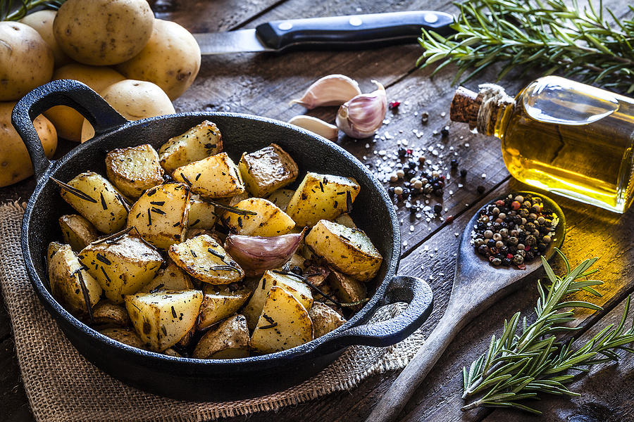 Roasted potatoes on wooden kitchen table Photograph by Fcafotodigital
