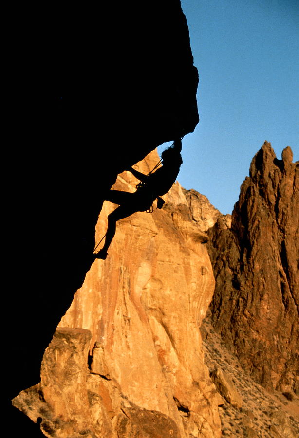 Rock climber climbing up rock overhang, silhouette Photograph by Karl Weatherly