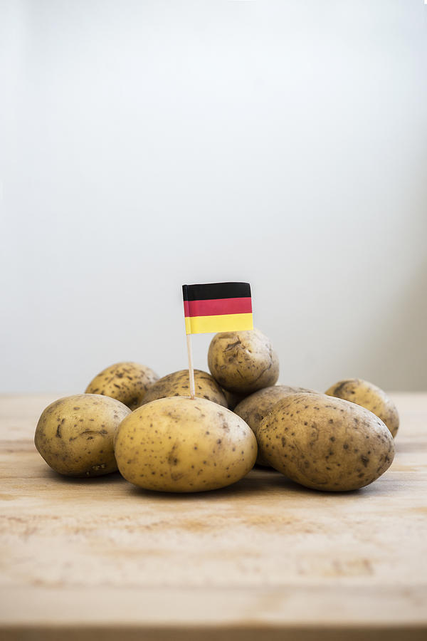 Row potatoes and small german little flag on wood Photograph by Westend61