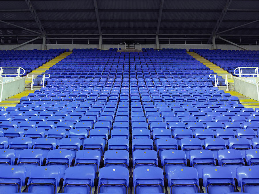 Rows of blue seats in stadium Photograph by Alan Thornton