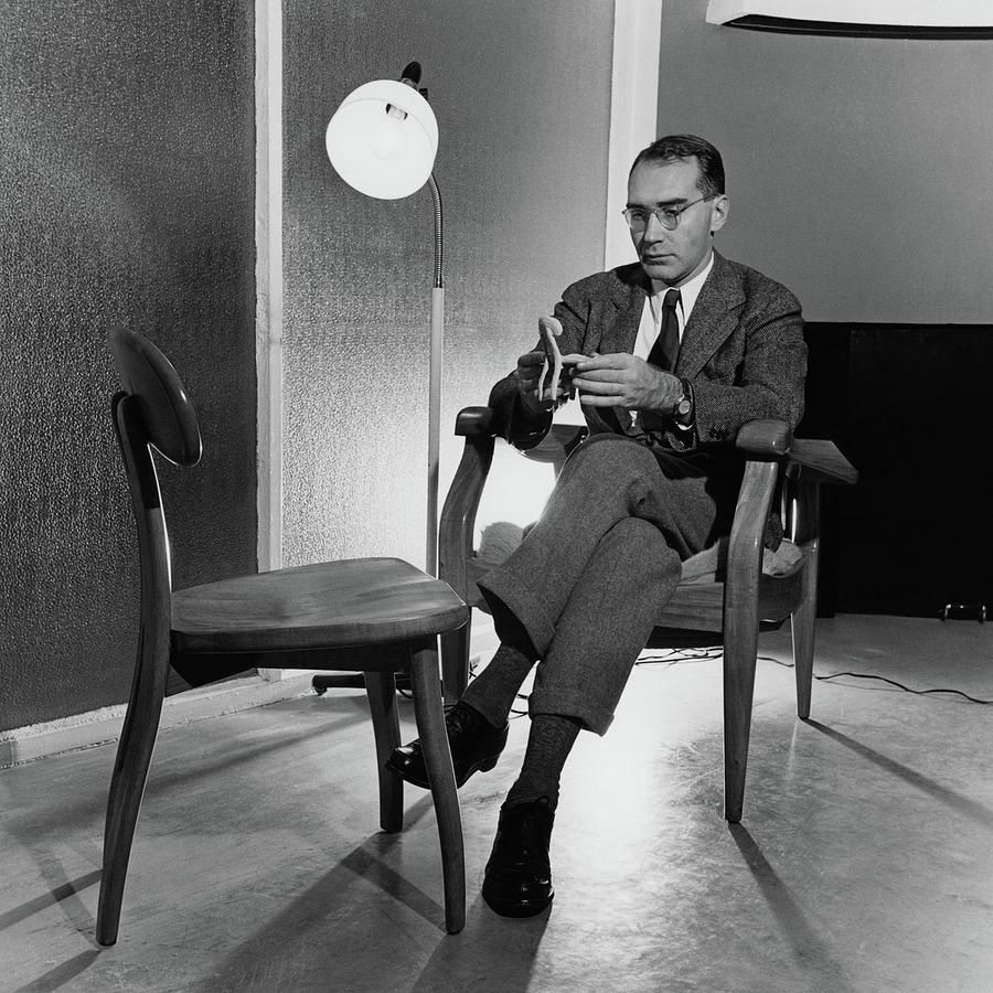 Russel Wright Sitting On A Chair Examining A Clay Photograph by Luis Lemus