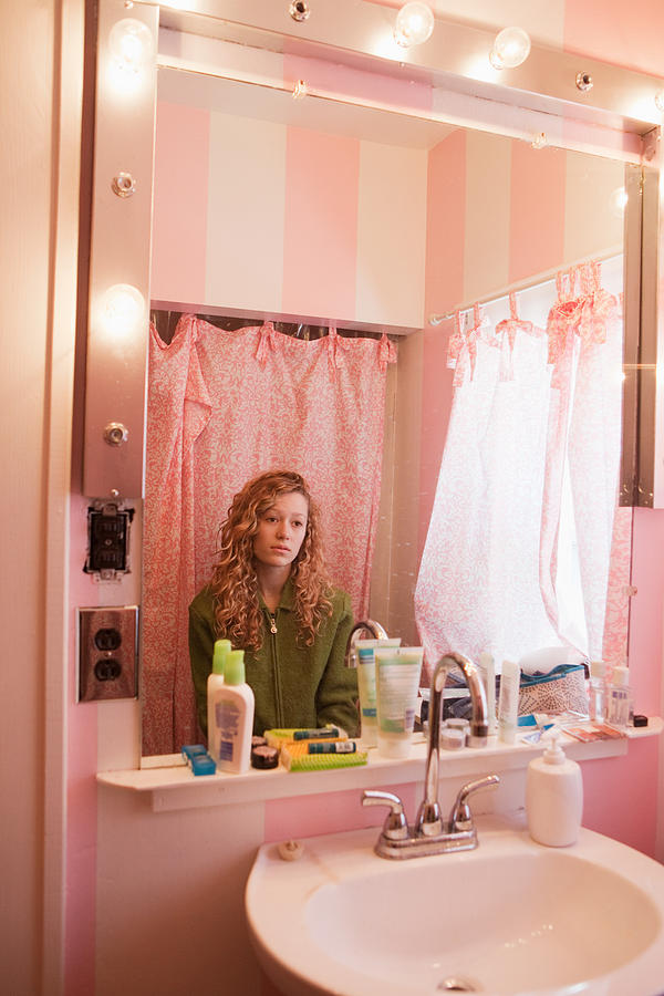 Sad teenage girl reflected in bathroom mirror Photograph by Image Source