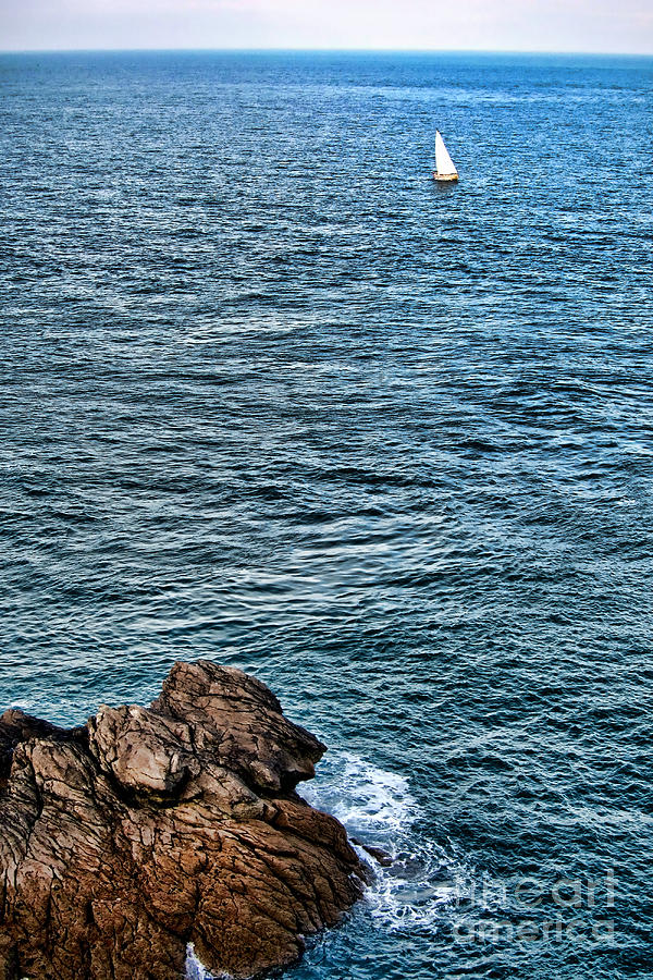 Sailboat along Rocky Coastline Photograph by Olivier Le Queinec