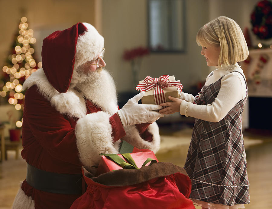 Santa Claus giving girl (4-5) gift, side view Photograph by Jose Luis Pelaez