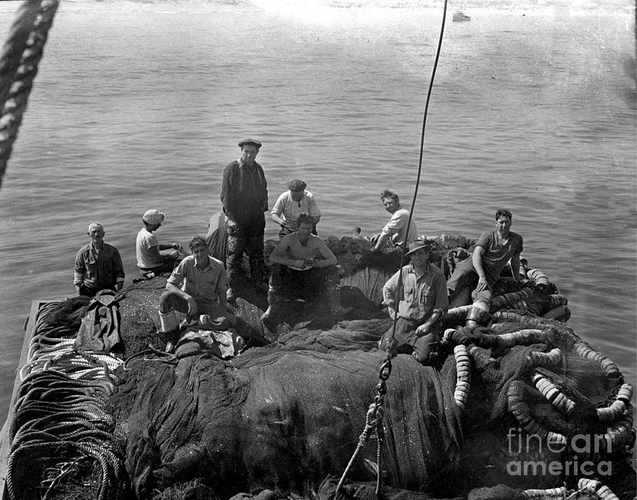 Sardine Photograph - Sardine fishermen sitting on nets on the turn-table on the back of the boat 1930 by Monterey County Historical Society