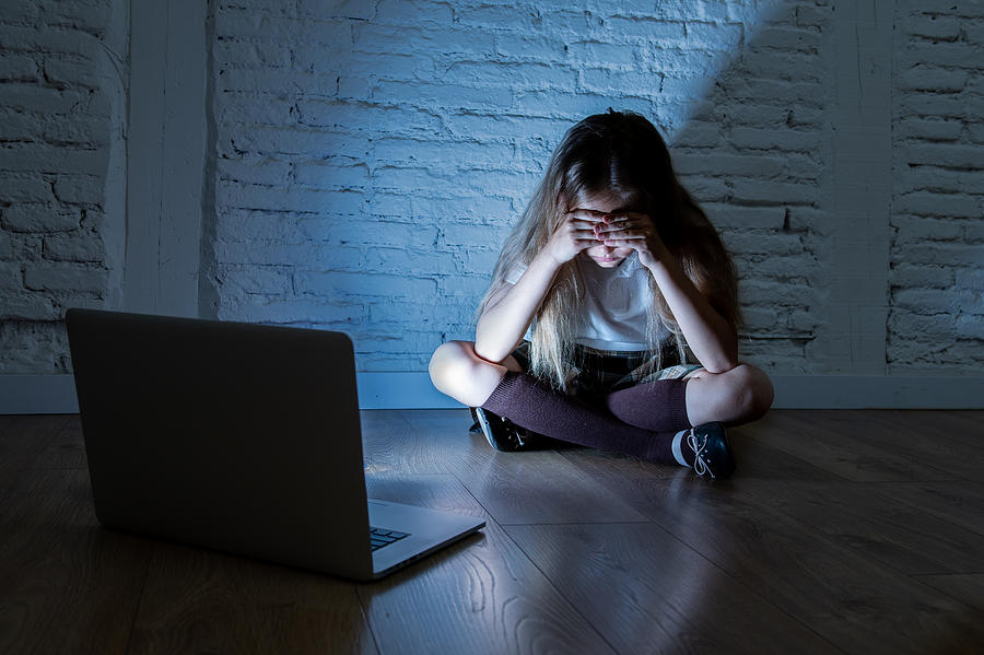 Scared sad girl bullied on line with laptop suffering cyberbullying and harassment feeling desperate and intimidated. Child victim of bullying stalker social media network Photograph by Sam Thomas