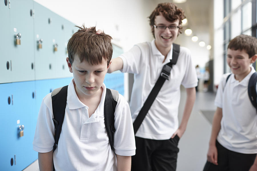 Schoolboy being bullied in school corridor Photograph by Phil Boorman