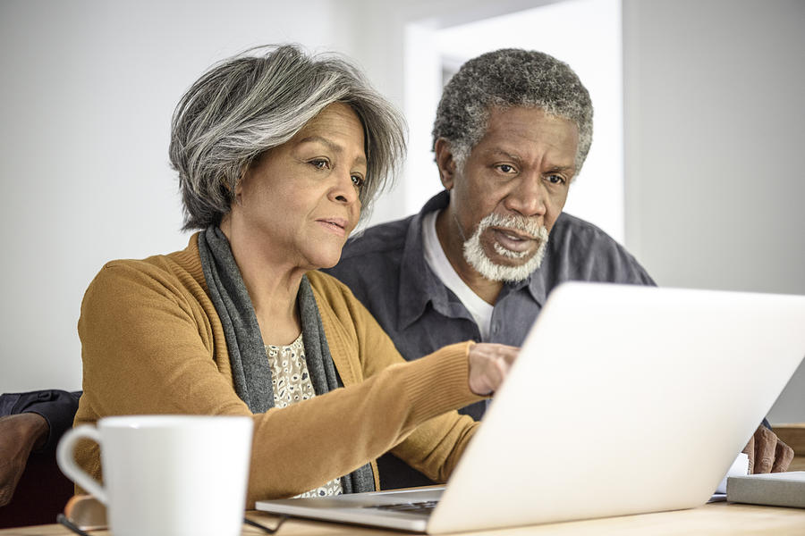 Senior African American couple on laptop together with serious expression Photograph by JohnnyGreig