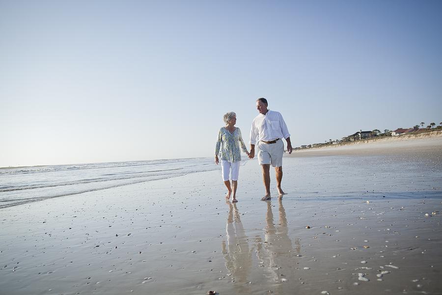 Senior couple with walking on beach holding hands Photograph by EVOK/M.Poehlman