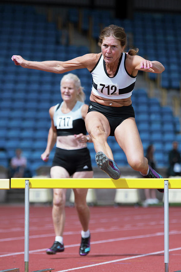 Senior Female Athlete Clears Hurdle Photograph by Alex Rotas