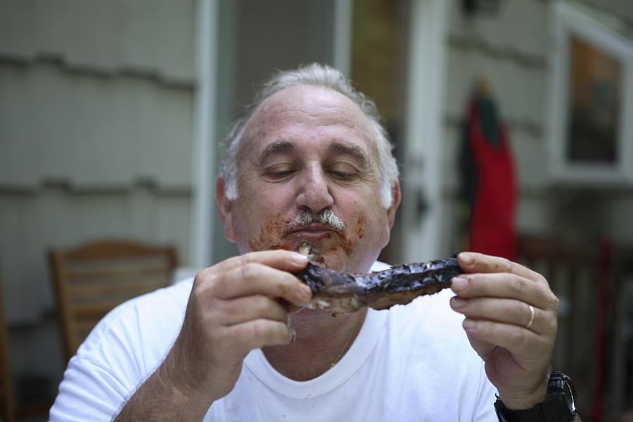 Senior man eating steak, outdoors Photograph by Allison Michael Orenstein
