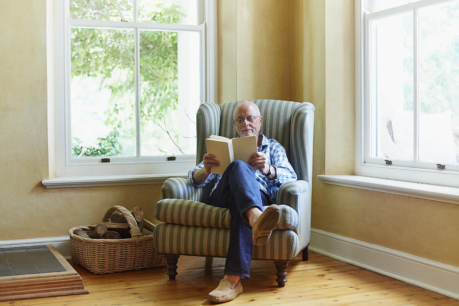 Senior man reading book at home Photograph by Morsa Images