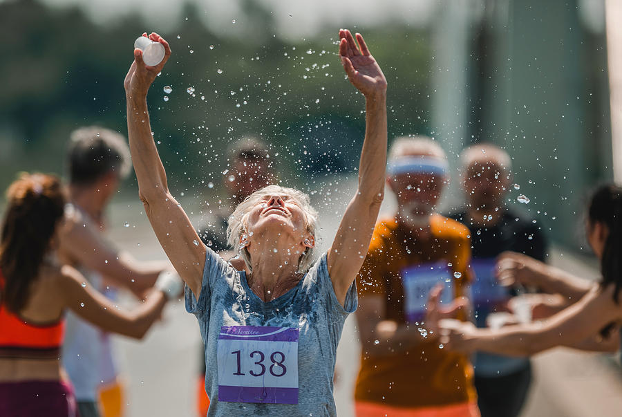 Senior marathon runner refreshing herself with water during a race. Photograph by Skynesher