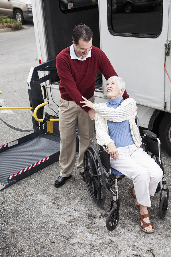 Senior woman by minibus with wheelchair lift Photograph by Kali9