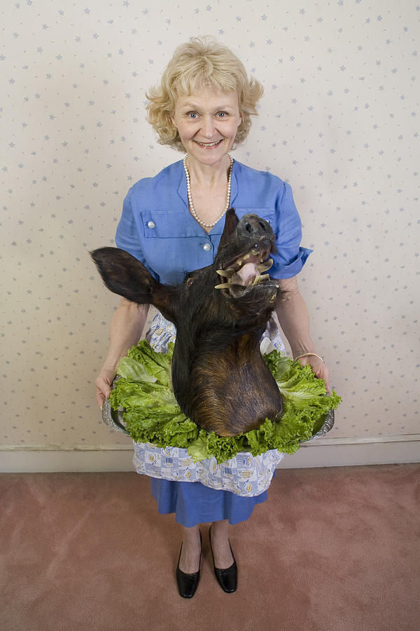 Senior woman holding wild boars head, portrait, high angle view Photograph by Sheer Photo, Inc
