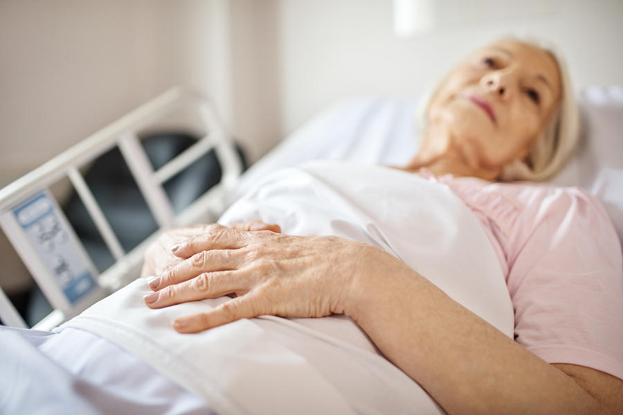 Senior woman lying on hospital bed Photograph by Alvarez