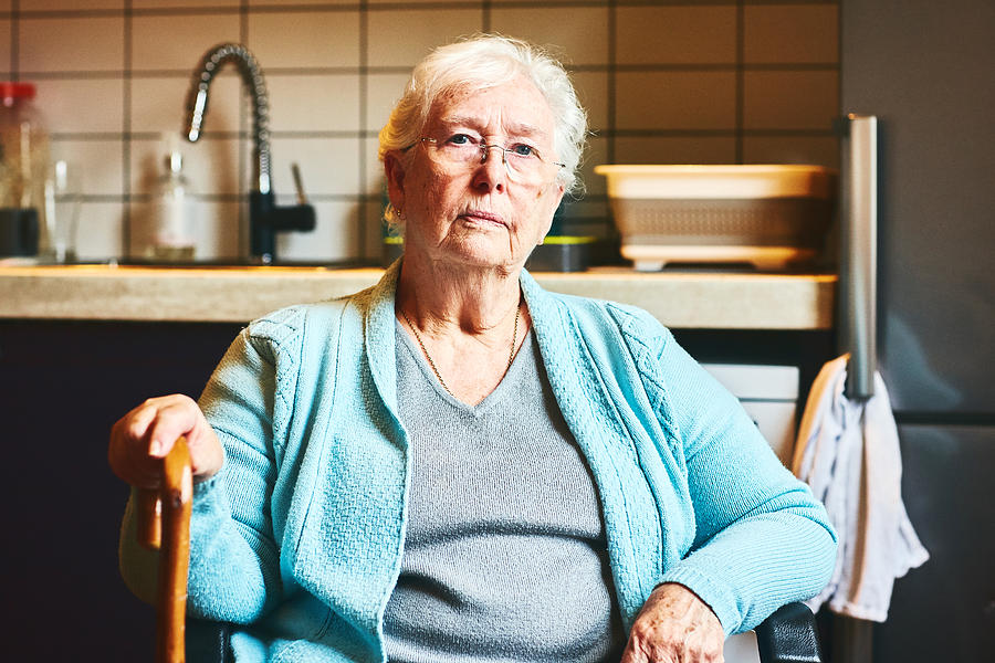 Senior woman sitting in kitchen Photograph by Dean Mitchell