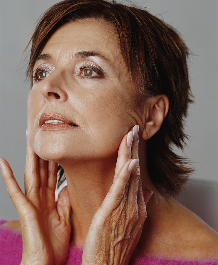Senior woman touching jaw line with fingers, close-up Photograph by Digital Vision