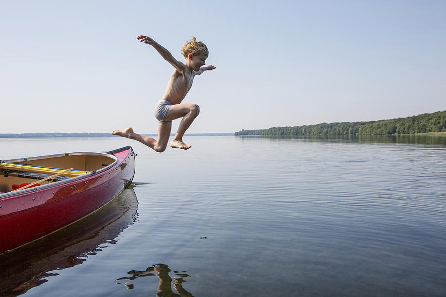 Seven year old boy jumping from a canoe. Photograph by David Trood