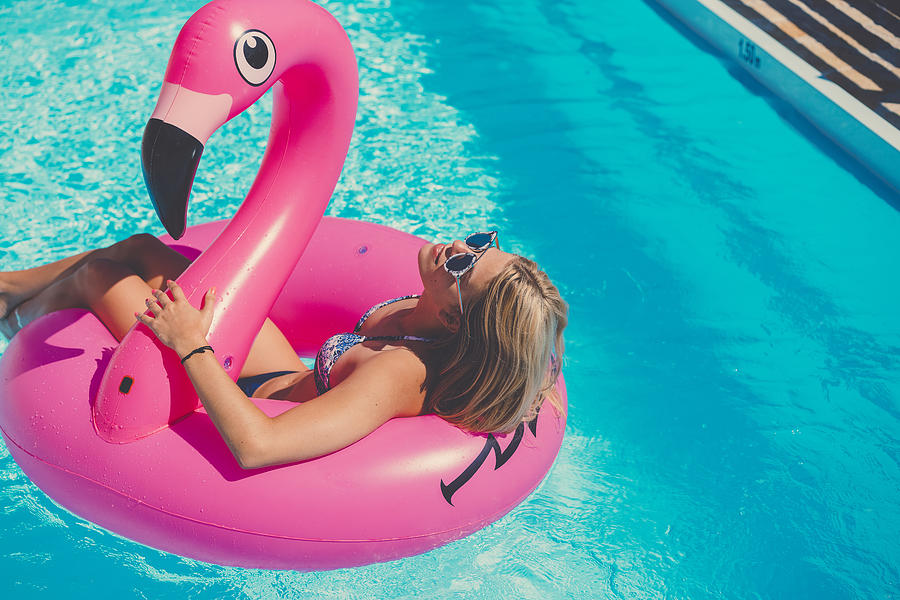 Sexy girl in bikini wearing sunglasses on inflatable flamingo Photograph by Spyderskidoo