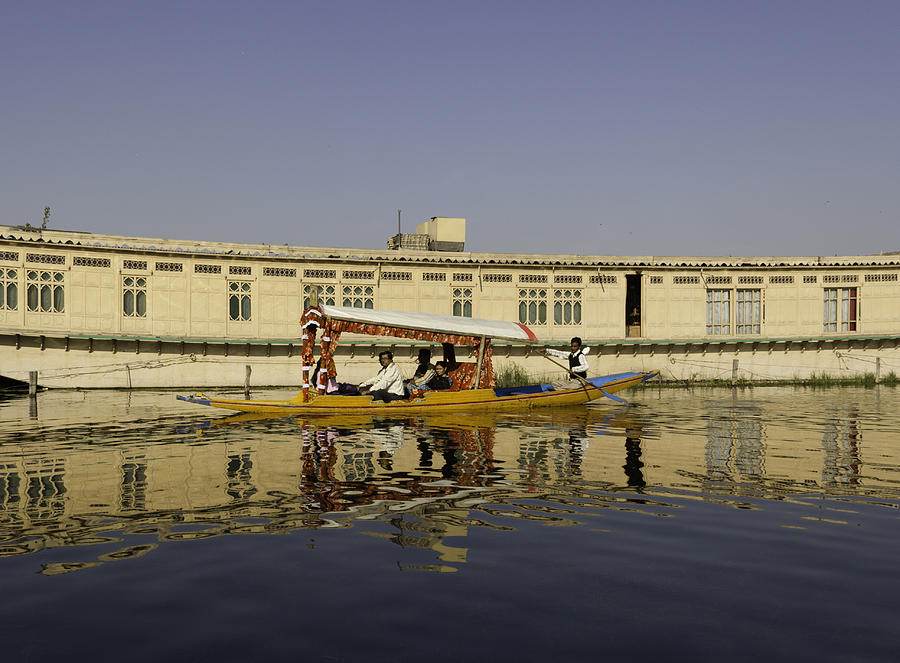 Shikara with tourists passing in front of a large houseboat in the Dal Lake Photograph by Ashish Agarwal