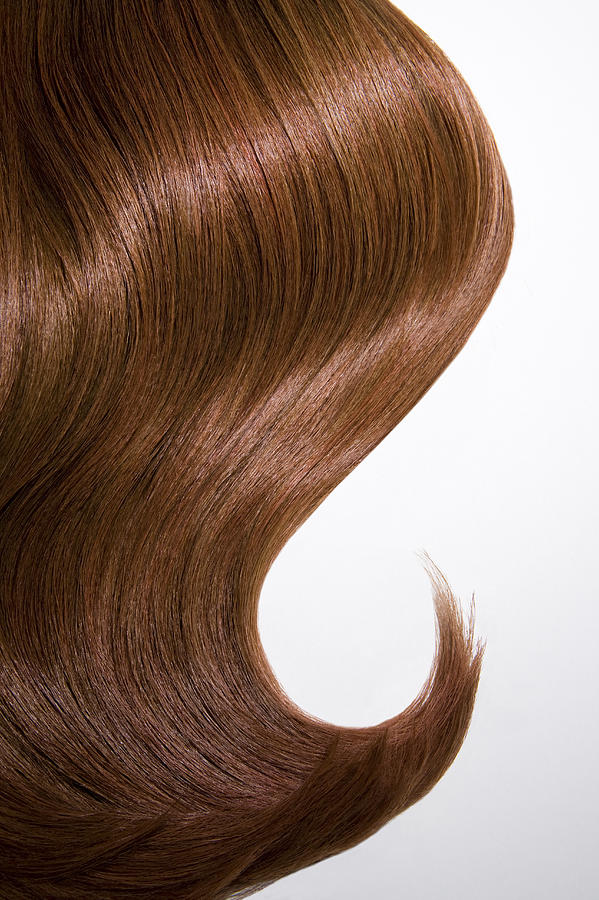 Shiny wavy red hair on white background, cropped. Photograph by Andreas Kuehn