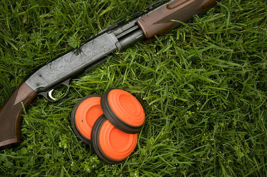 Shotgun and clay pigeons laying in grass Photograph by Photographer3431