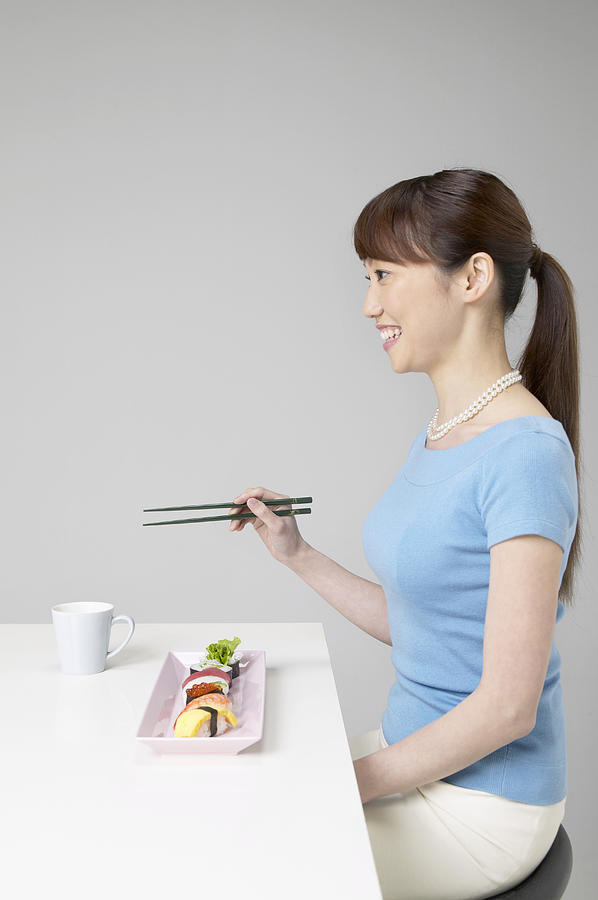 Side View of a Woman Sitting at a Table Eating Food With Chopsticks Photograph by Mash