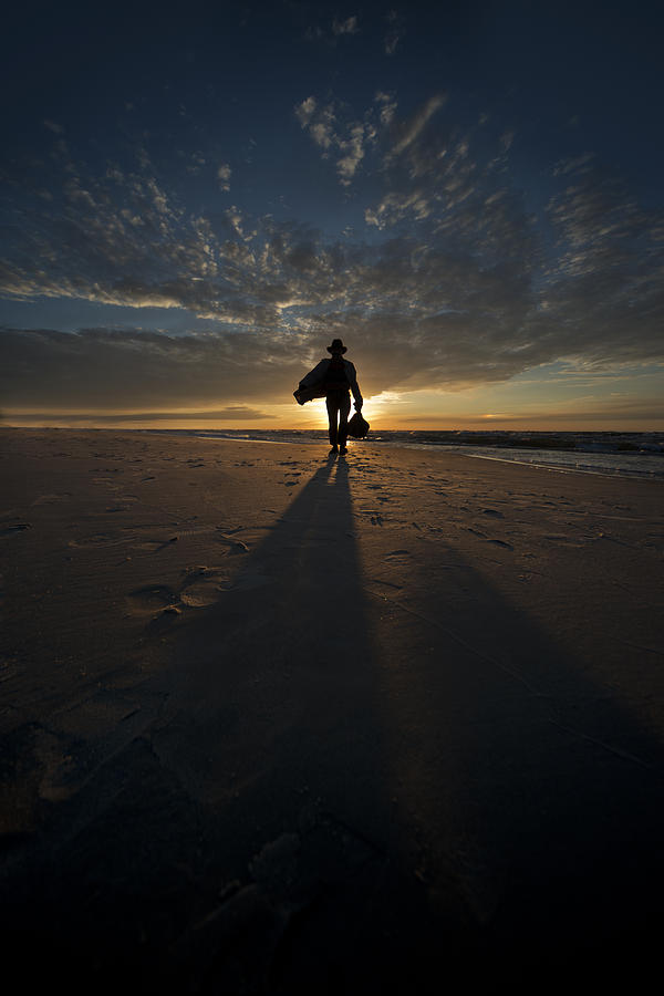 Silhouette of a man wearing hat and the bag in hand walking on the seashore Photograph by Jaroslaw Blaminsky