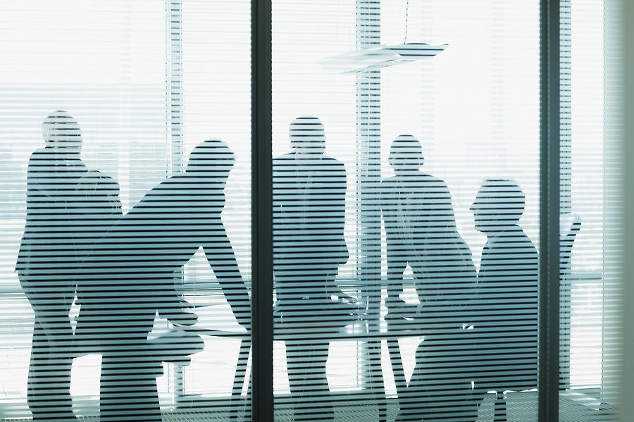 Silhouette of business people leaning on table in conference room Photograph by Martin Barraud